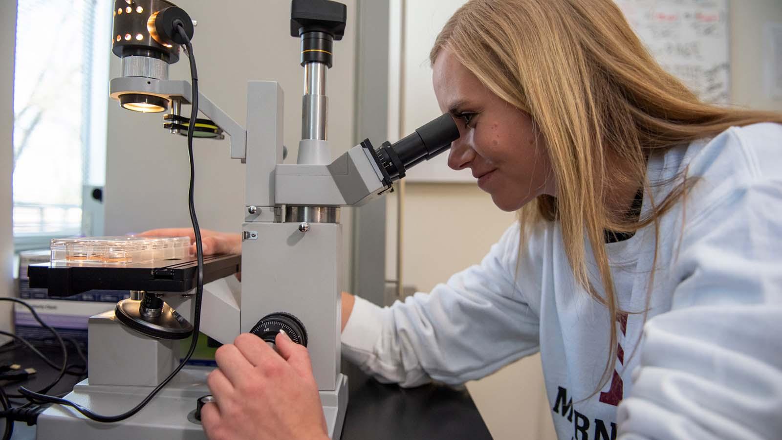A Morningside student using a microscope.